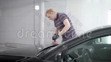 工人正在<strong>汽车服务</strong>中打磨黑色汽车引擎盖，用软抹布擦洗车身